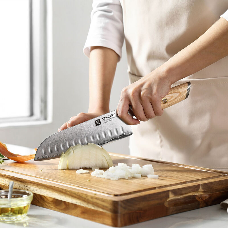 a person use XINZUO B37S Lan Santoku Knife 7“ cutting onions on a cutting board